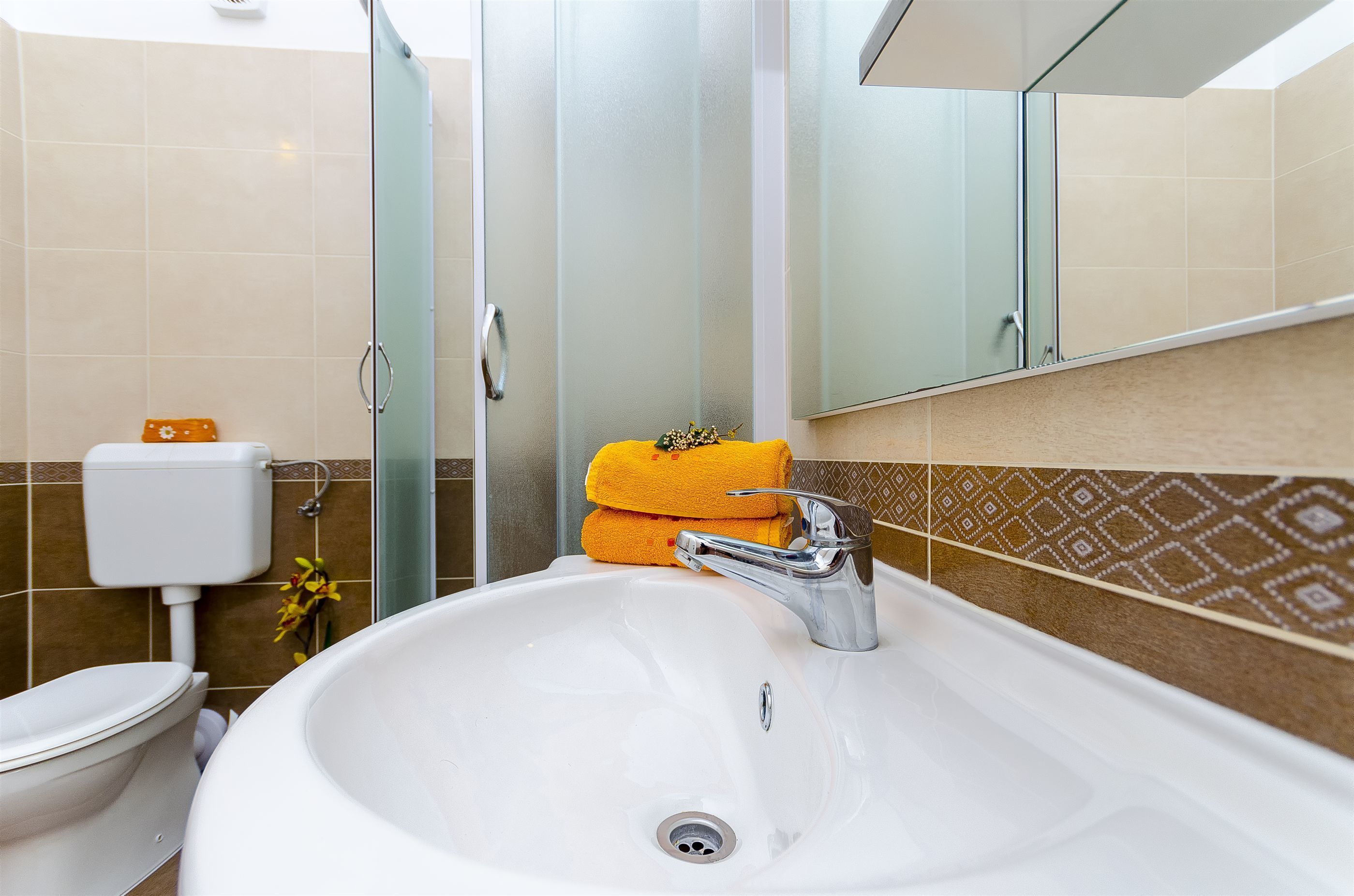 A bathroom with a white sink, a glass shower enclosure, and a toilet.