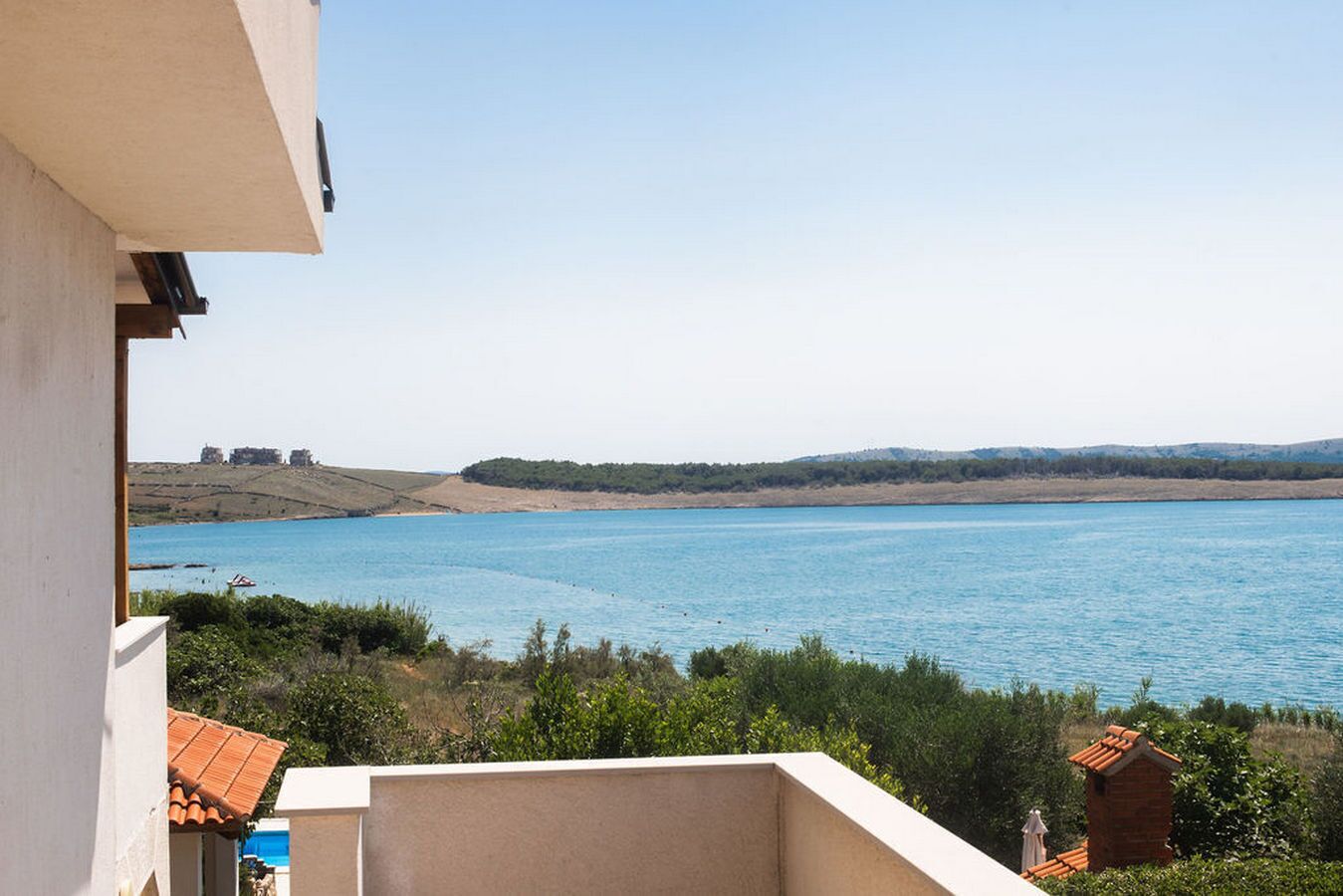 Une vue d’un lac paisible, avec une colline au loin et un bâtiment sur la gauche.
