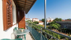 Ein Balkon mit Tisch und Stühlen, der auf ein Wohngebiet mit Häusern und Grünflächen blickt.