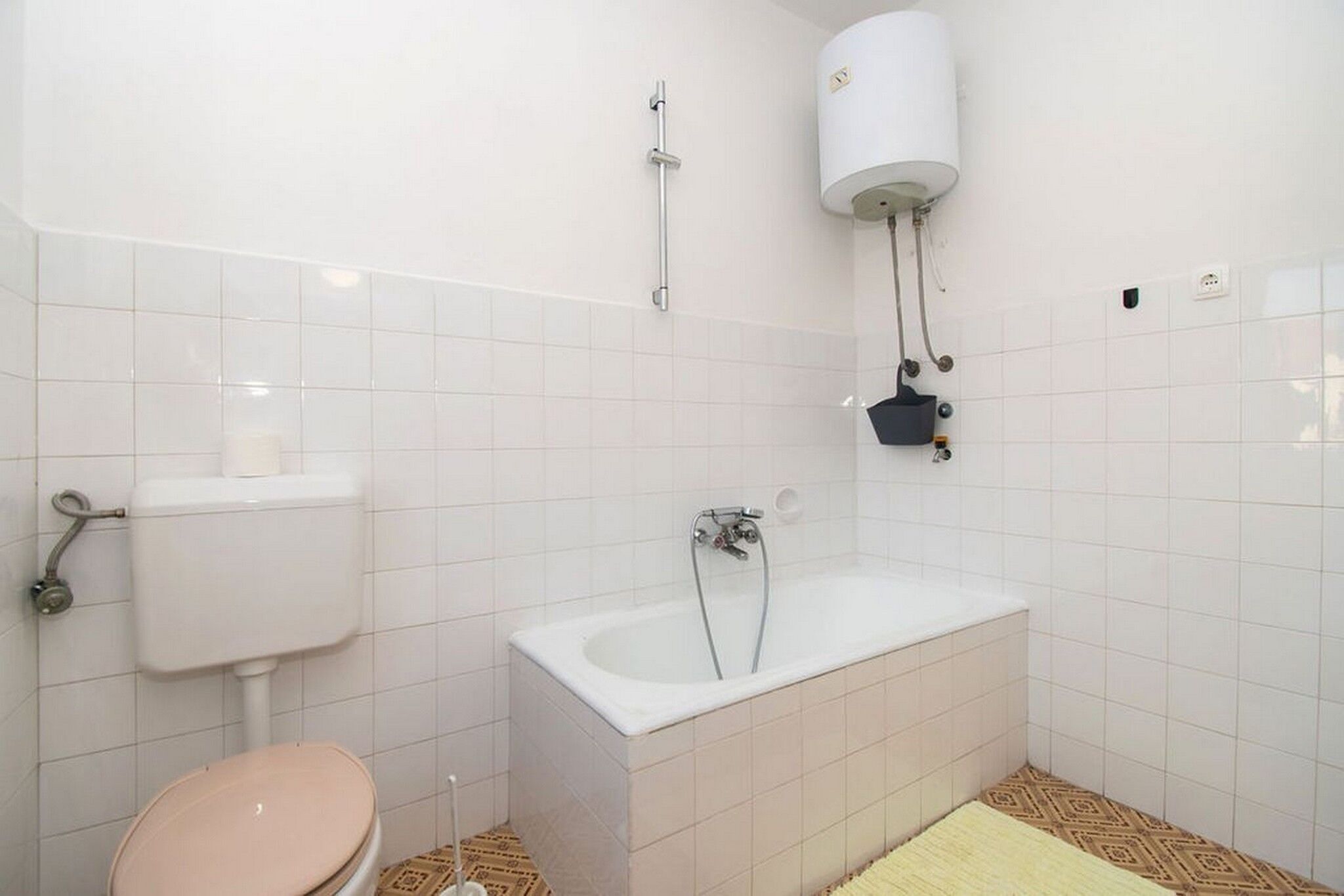 A bathroom with a toilet, sink, bathtub, and a toilet paper holder.