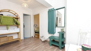 A room with a wooden floor, a green bench, a white chair, a table with a cake, and a mirror on the wall. - Apartment Sandra (Vodice)
