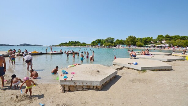 A beach with people swimming and sunbathing, a lifeguard tower, and a clear sky. - Apartment Lena City Center Near Beach (Vodice)