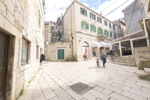 A narrow street with stone buildings, a shop named 'Admiral', and a man walking with a child.