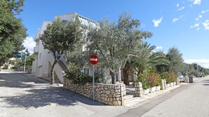 A street with a no entry sign, a stone wall, and a white building with blue shutters. - Apartments Family Gligora (Mandre)