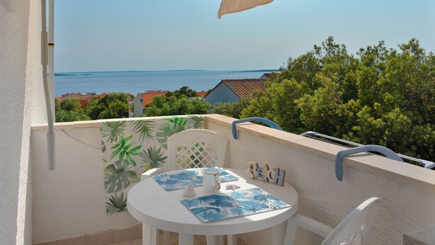 A balcony with a table, chairs, and a view of the sea. - Apartments Family Gligora (Mandre)
