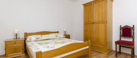 A bedroom with a wooden bed, nightstands, a wardrobe, and a chair.