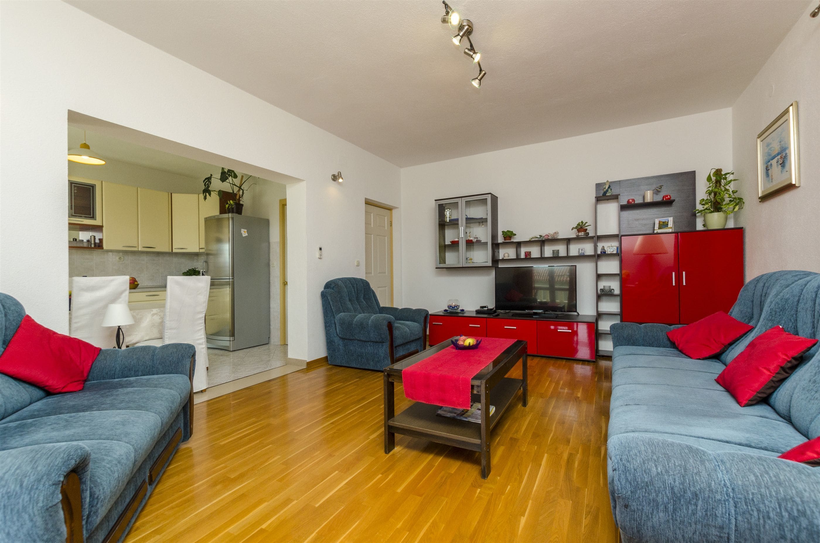 A living room with two blue sofas, a red cabinet, and a TV.