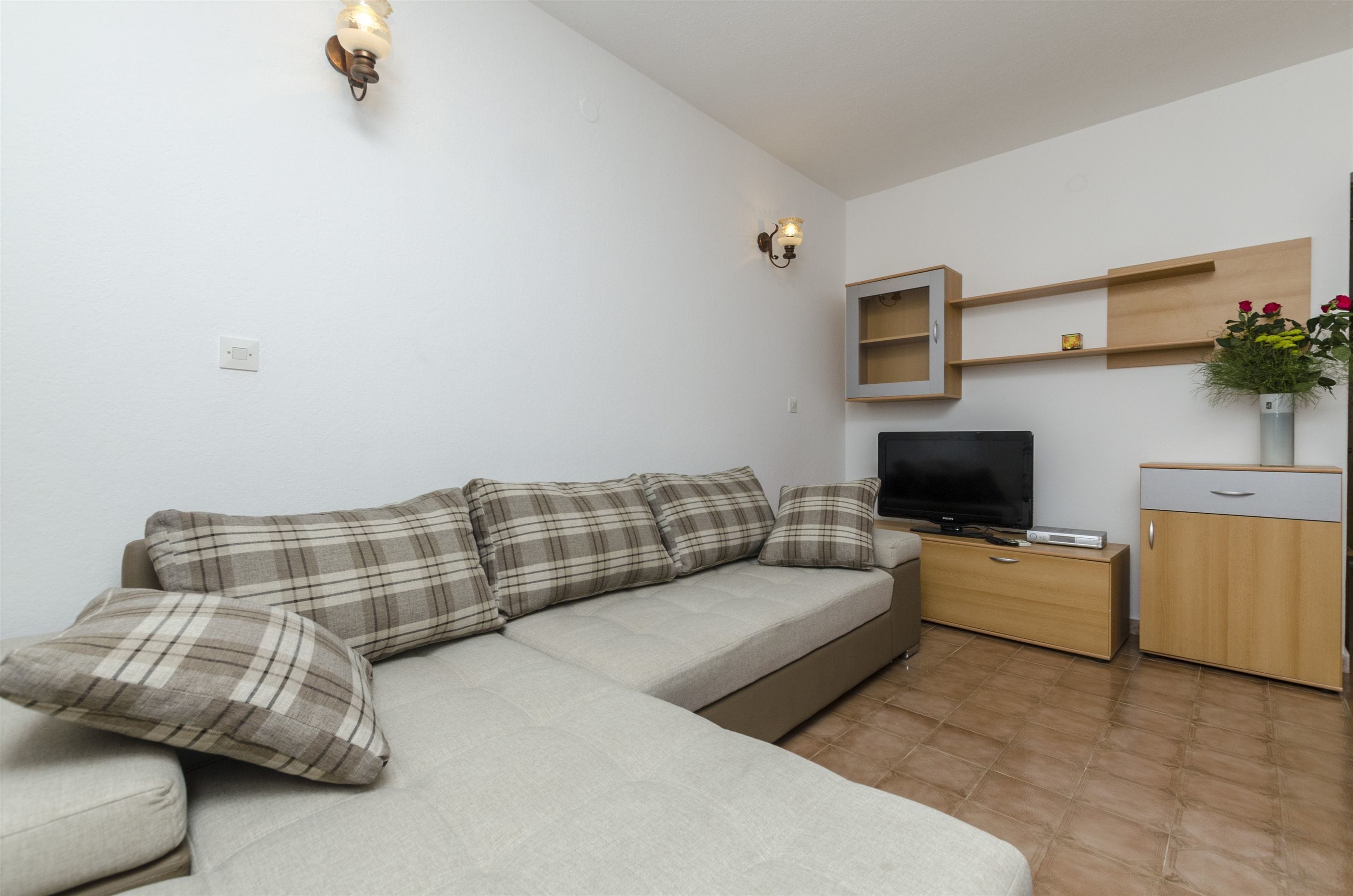 A modern living room with a sofa, TV, wooden cabinet, and wall-mounted shelves.
