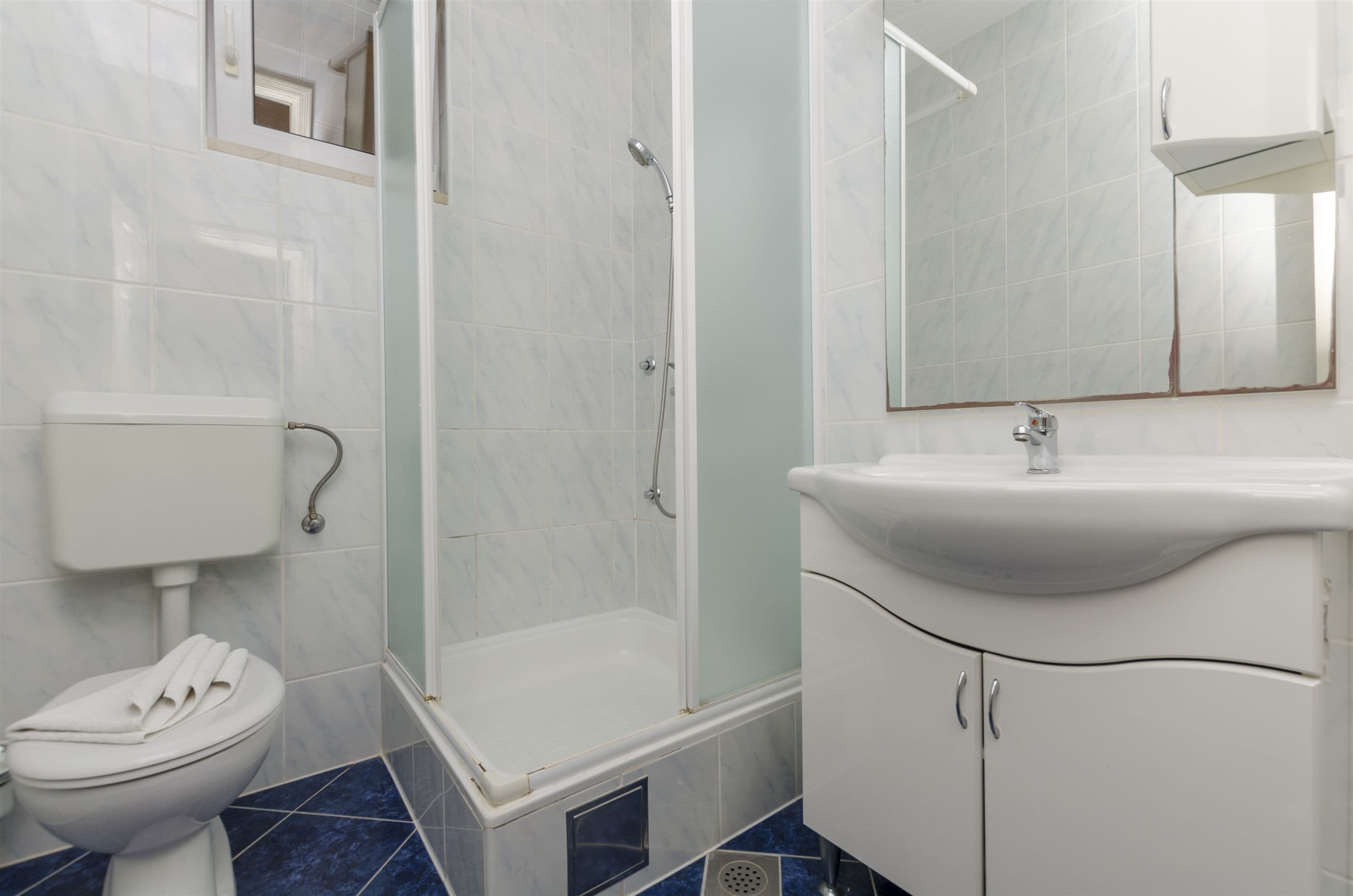 Un baño con inodoro, cabina de ducha y lavamanos con espejo.