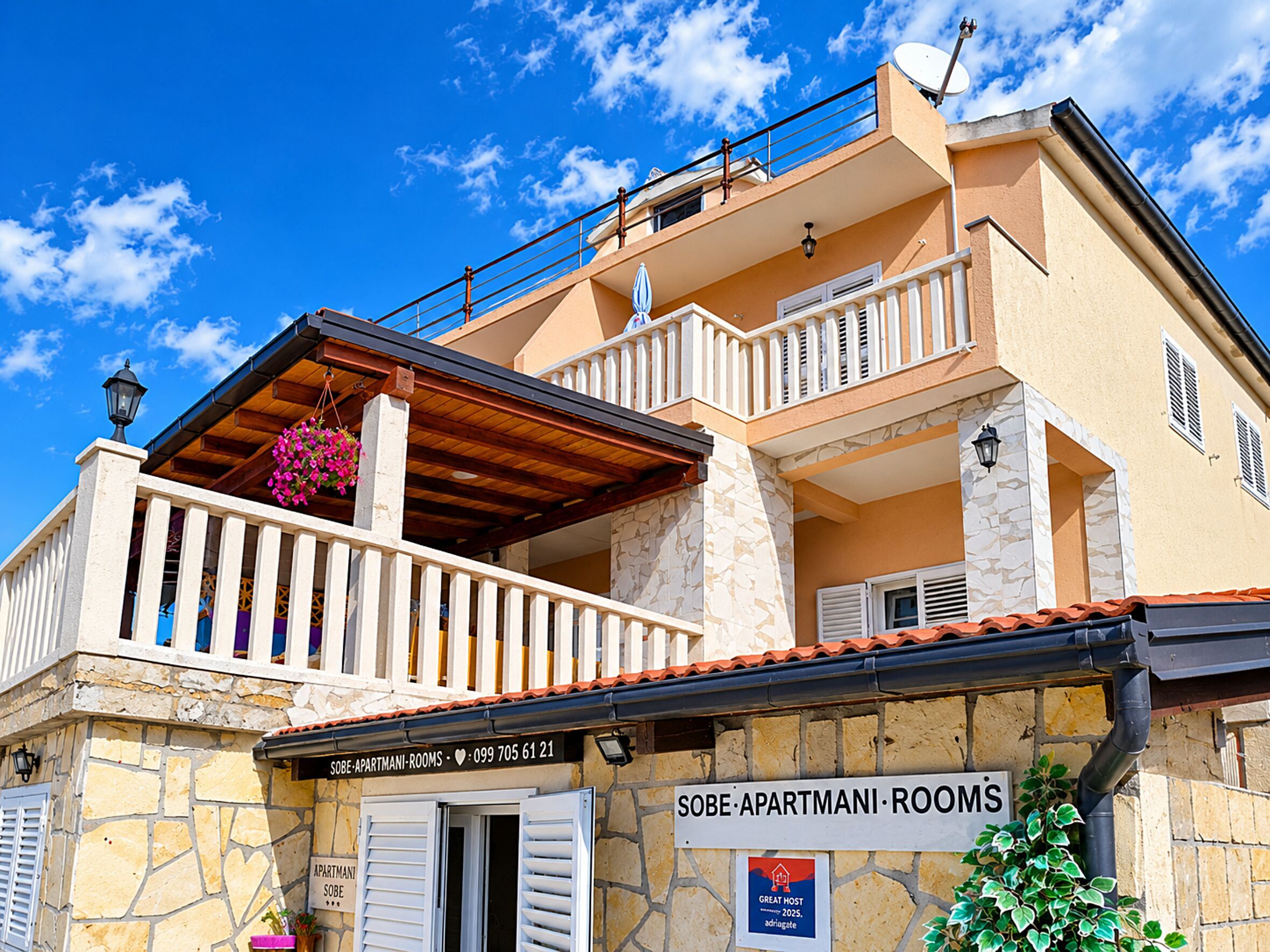 Un edificio de dos pisos con fachada de piedra, balcones con barandillas blancas y un letrero que dice 'SOBE APARTMANI ROOMS'.