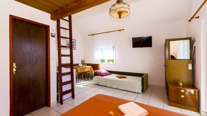 A room with a wooden door, a ladder, a sofa, a TV, a mirror, and a small table with a lamp. - Apartments Pera (Razanj)