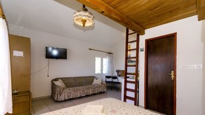 A bedroom with a bed, a wooden ceiling, a TV, a sofa, a desk, and a wardrobe. - Apartments Pera (Razanj)