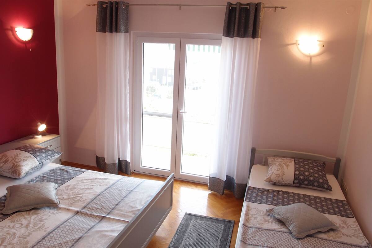 A hotel room with two beds, a sliding glass door to the outside, and a red accent wall.