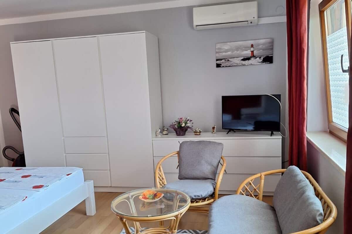 A compact living space with a sofa set, a glass coffee table, a TV, and a wardrobe.