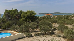Ein Poolbereich mit freiem Blick auf das Meer und Hügel im Hintergrund.