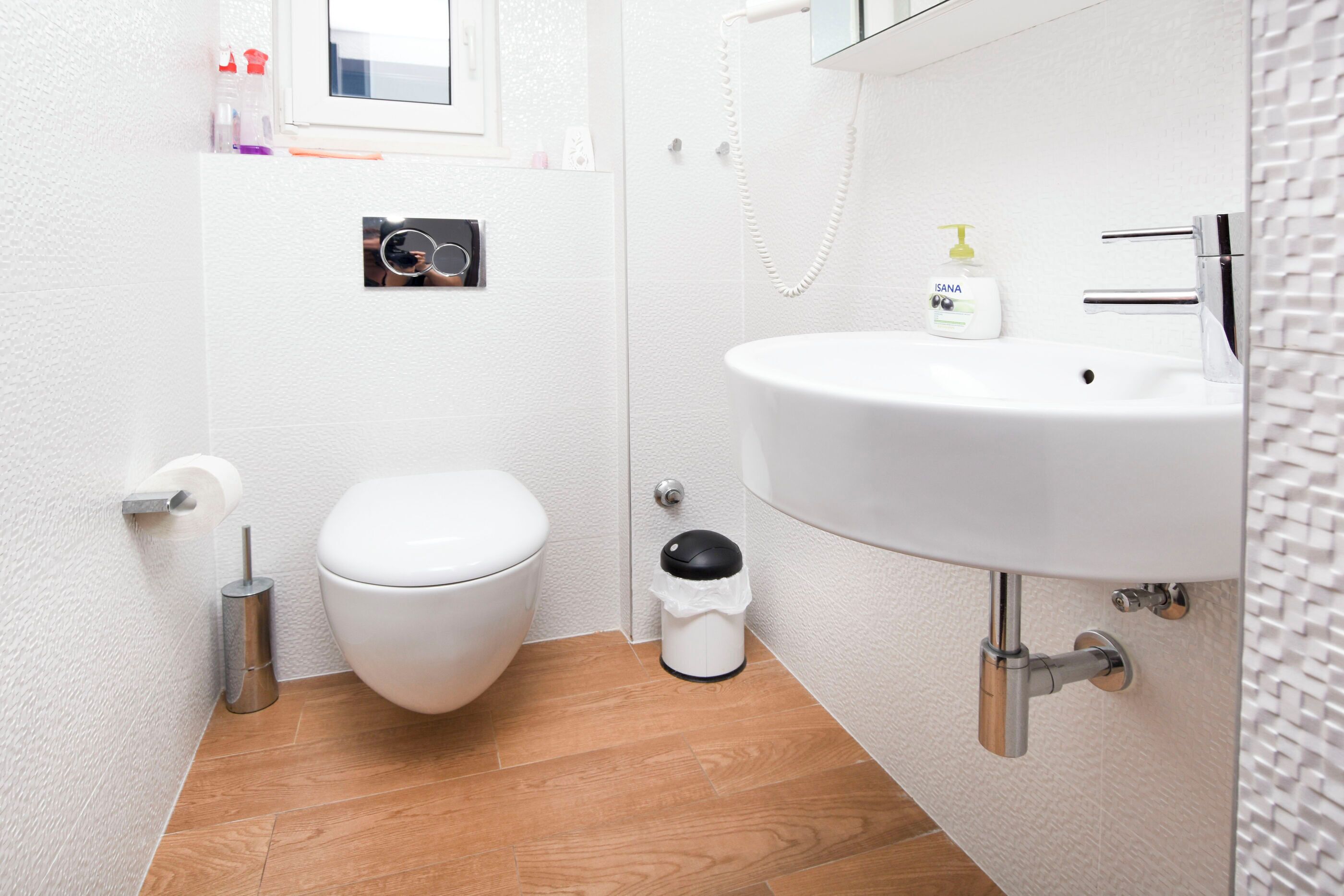 Et stilfuldt badeværelse med toilet, vask og skraldespand.