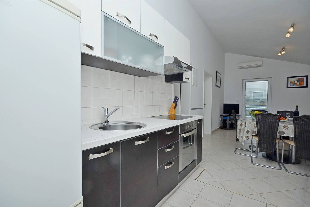 Une cuisine moderne dotée d’un four encastré, d’un évier et d’un coin repas avec une table et des chaises.