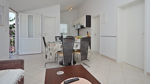 A compact living space with a dining area, kitchenette, and a door leading to a balcony. - Apartments Sime (Srima)