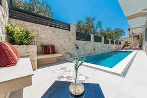 Ein Poolbereich mit Steinmauer, Bank und dekorativer Vase.