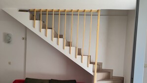 A staircase with wooden handrails, a red sofa with green cushions, and a tiled floor. - Apartments Emil (Murter)