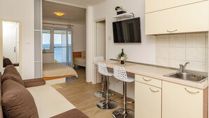 Un espace de vie compact comprenant un coin cuisine, un lit, une télévision et un balcon avec vue.