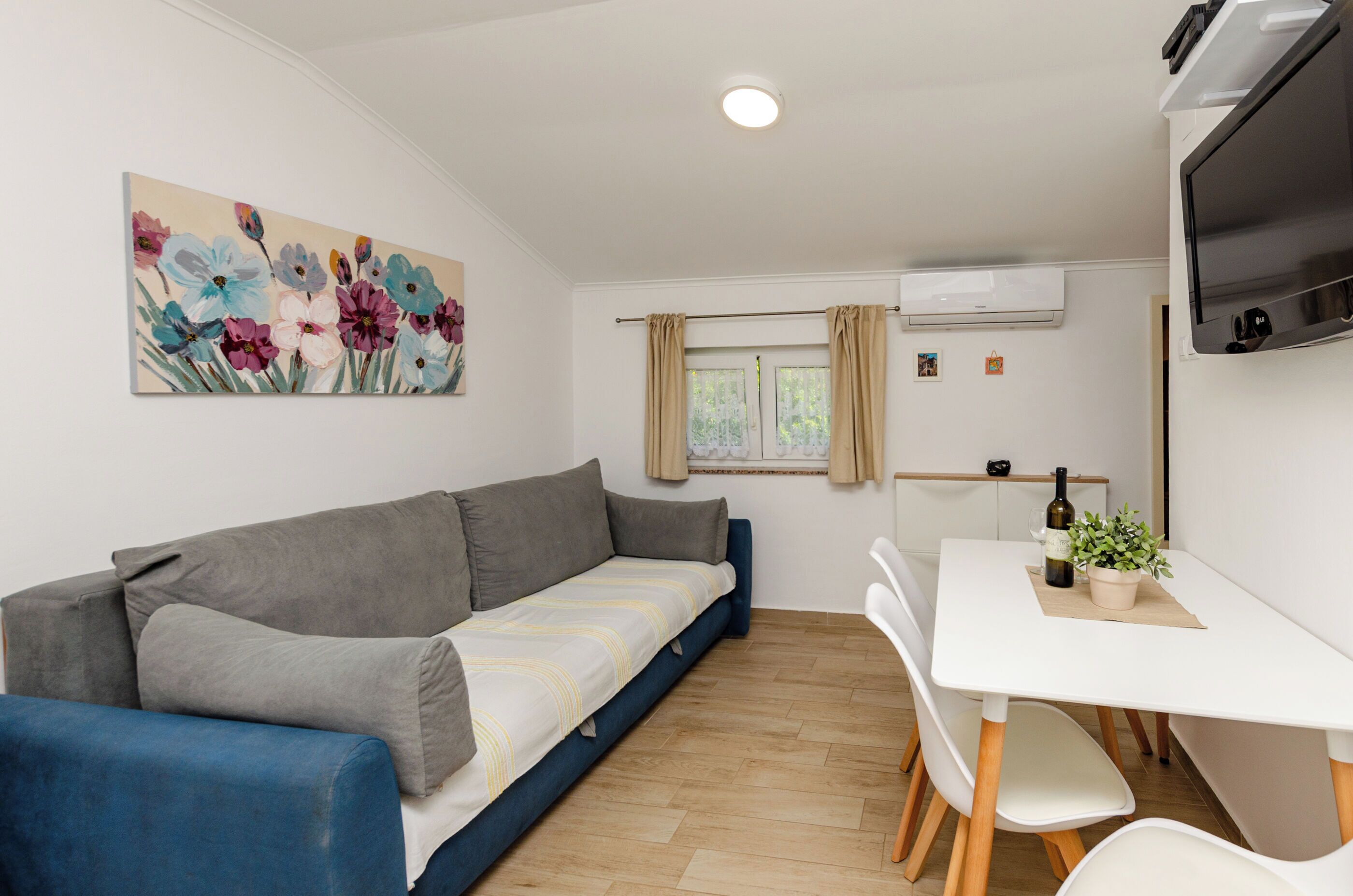 A modern living room with a sofa, a dining table, and a TV.
