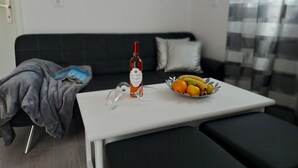 A modern living room with a white table, a bottle of wine, and a bowl of fruit. - Apartments Karlo (Bol)