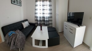 A modern living room with a sofa, a coffee table, a TV, and a cabinet. - Apartments Karlo (Bol)