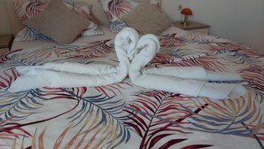 A bed with a floral-patterned bedspread, two pillows, and a rolled towel on the bed. - Apartments Karlo (Bol)