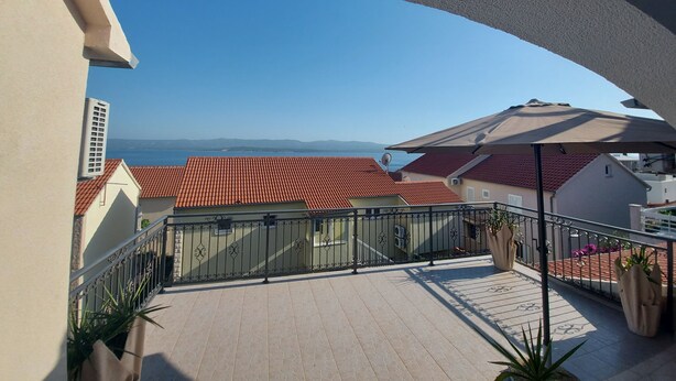 A balcony with a view of the sea and red-roofed buildings. - Apartments Karlo (Bol)