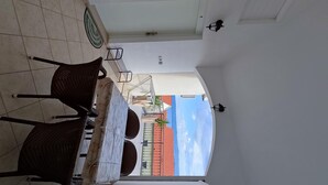 A dining area with a table and chairs, a view of buildings through an open door, and a ceiling fan. - Apartments Karlo (Bol)