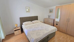 A bedroom with a bed, a nightstand, a dresser, and a wardrobe.
