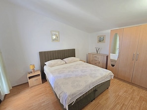 Ein Schlafzimmer mit Bett, Nachttisch, Kommode und Kleiderschrank.