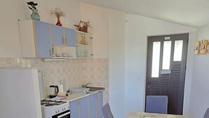 A compact kitchen with a gas stove, oven, and a dining area with a table and chairs.