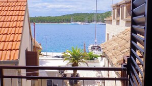 A coastal view with a marina, buildings with terracotta roofs, and a clear sky.
