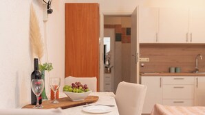 A dining area with a table set for two, a bottle of wine, and a bowl of grapes. - Apartments Ivana (Nin)