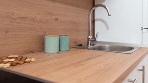 A kitchen with a wooden countertop, a stainless steel sink, and two patterned containers. - Apartments Ivana (Nin)
