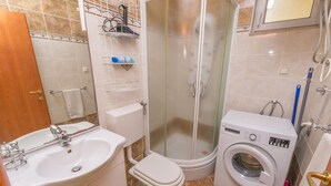 A bathroom with a sink, toilet, shower, and washing machine. - Apartment Mario (Rogoznica)