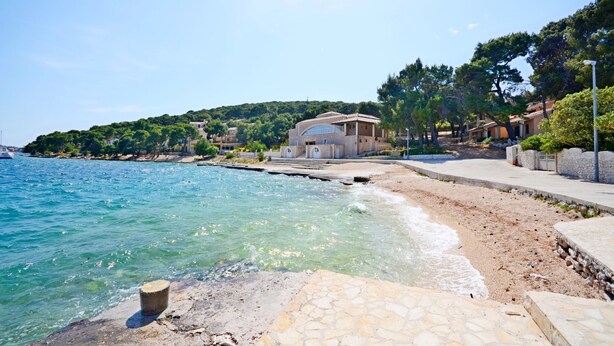 A coastal area with a beach, a stone pathway, and a building with a dome structure. - Apartment Mario (Rogoznica)