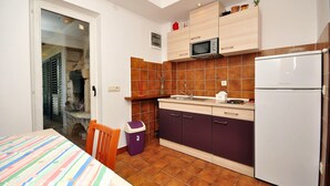 A compact kitchen with a microwave, refrigerator, and wooden cabinets. - Apartments Marin (Novalja)