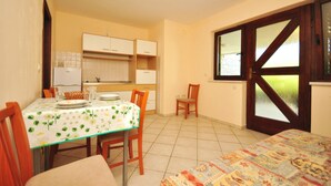 A compact kitchen with white cabinets, a dining table with chairs, and a large window with a view. - Apartments Marin (Novalja)