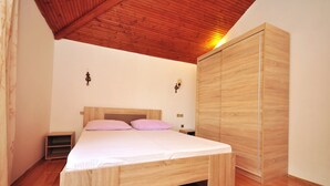 A bedroom with a wooden bed frame, a wardrobe, and a nightstand. - Apartments Marin (Novalja)