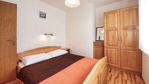 A bedroom with a bed, wooden wardrobe, and a nightstand. - Apartments Vladimir (Vodice)