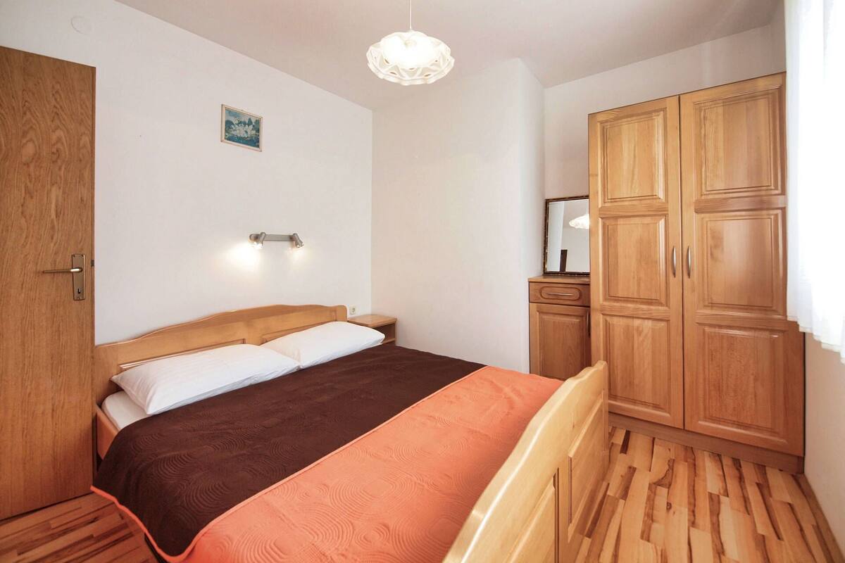 A bedroom with a bed, wooden wardrobe, and a nightstand.