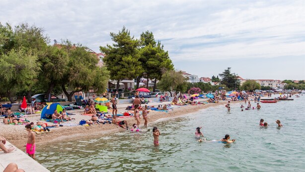 A crowded beach with people sunbathing and swimming. - Apartments Vladimir (Vodice)