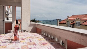 A balcony with a table set for two, overlooking a coastal view. - Apartments Vladimir (Vodice)