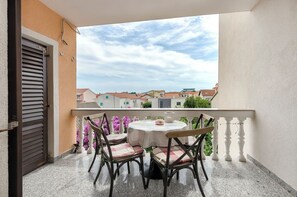 A balcony with a table and chairs, a view of buildings, and a door. - Apartments Miljenka (Vodice)