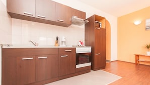 A modern kitchen with wooden cabinets, a built-in oven, and a coffee maker. - Apartments Tatjana (Sukosan)