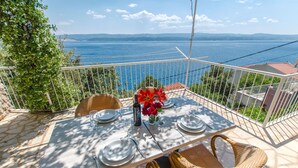 A terrace with a table set for two, overlooking a body of water. - Apartments Vedran (Stanici)