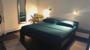 A modern bedroom with a bed, bedside tables, a mirror, and a potted plant. - Apartments Vedran (Stanici)